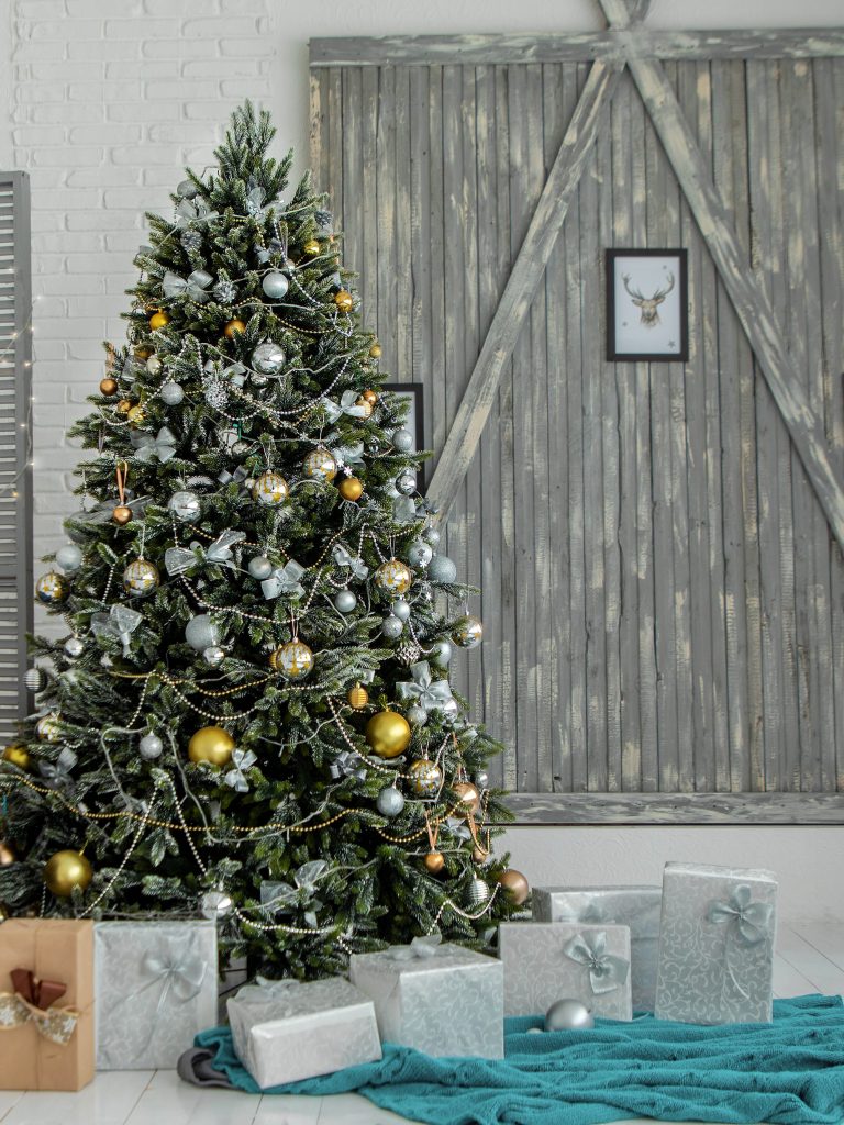 christmas tree and gifts in front of wood wall